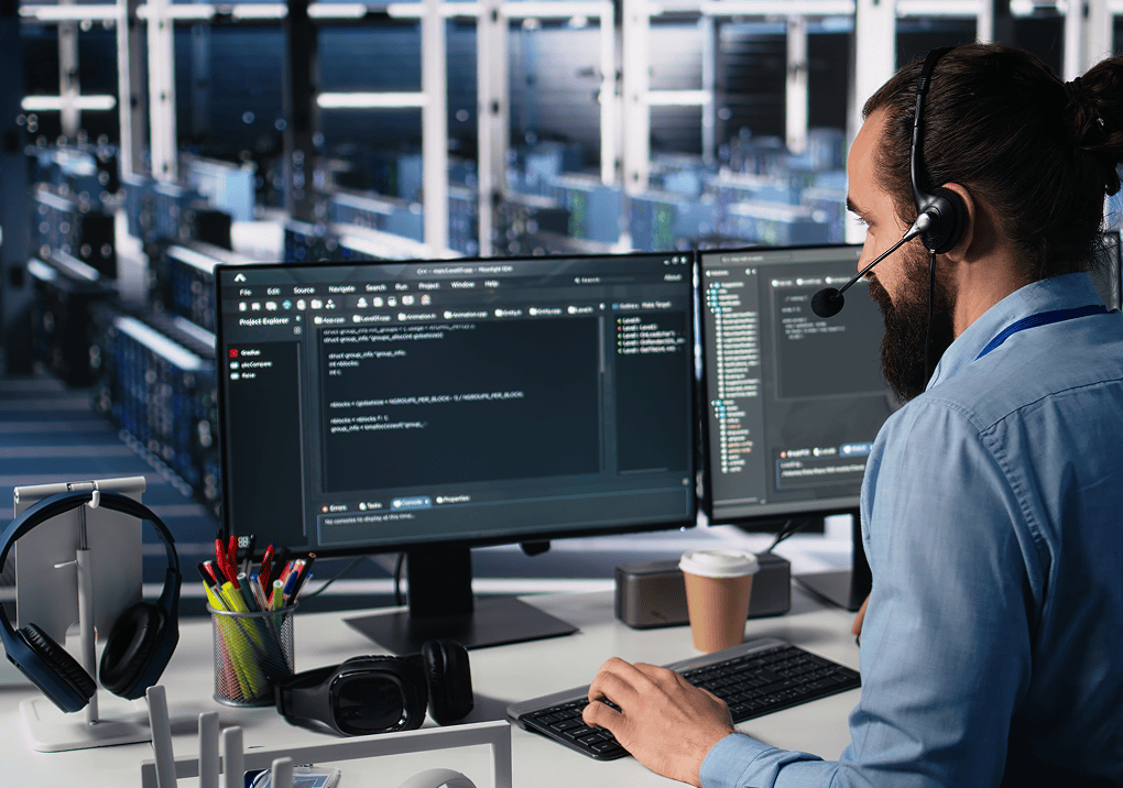 Programmer with headset at dual monitors