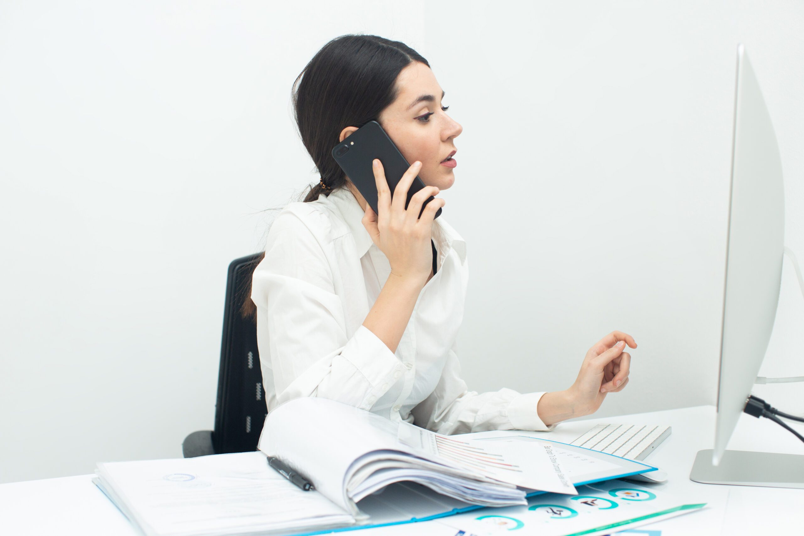 Businesswoman talking on phone at computer